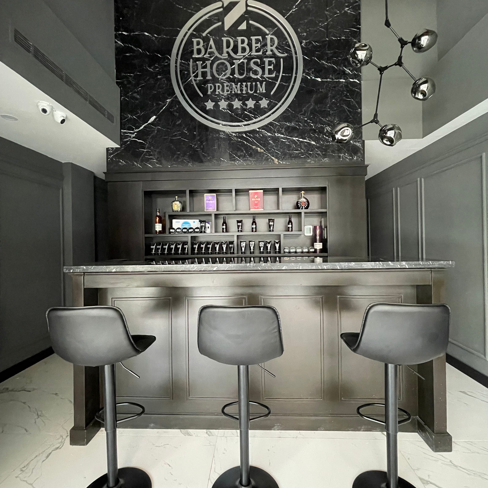 Zona premium con pared de mármol negro y logo Barber House Premium